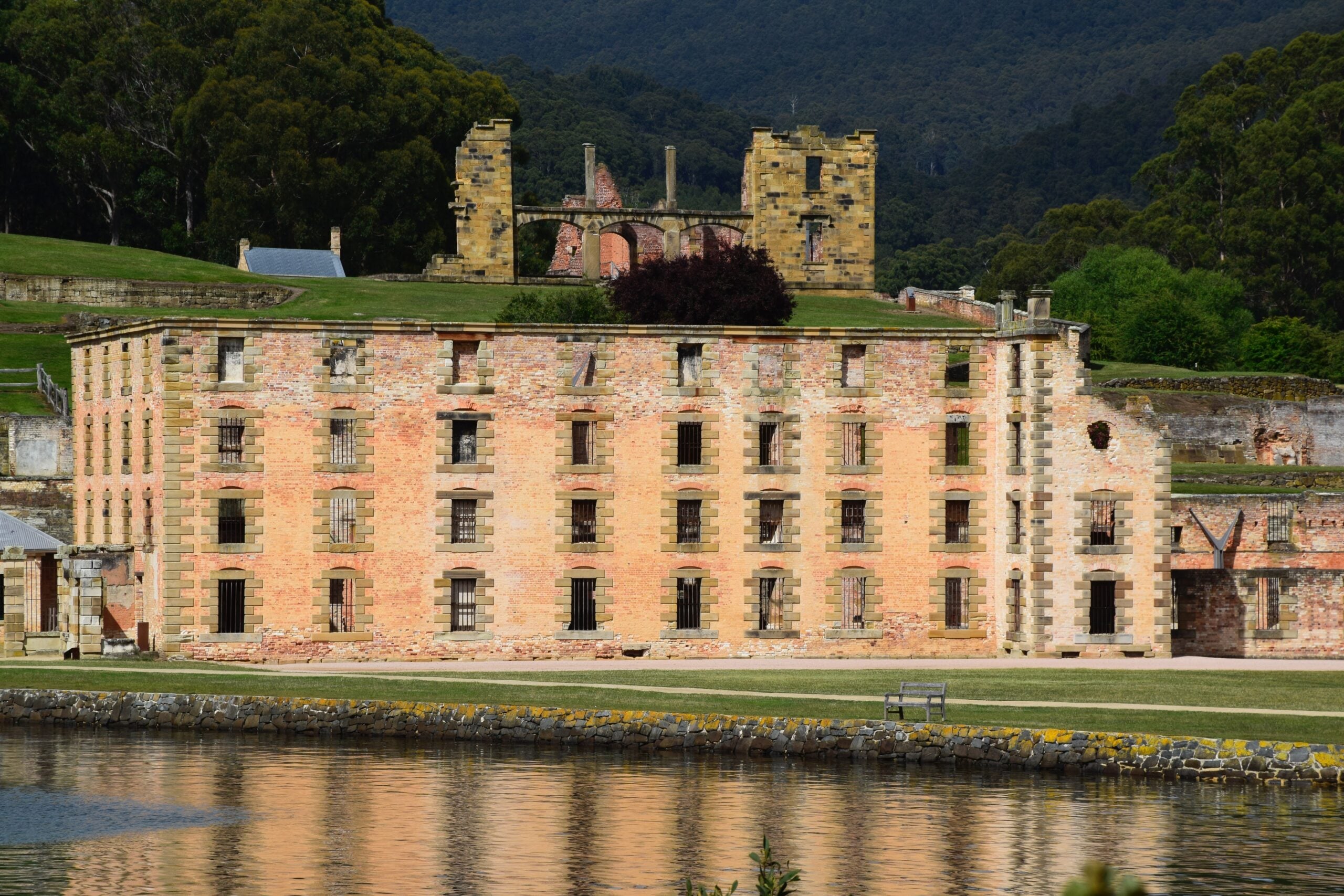 Historic brick ruins of the penitentiary building at Port Arthur Historic Site, Tasmania, with forested hills in the background